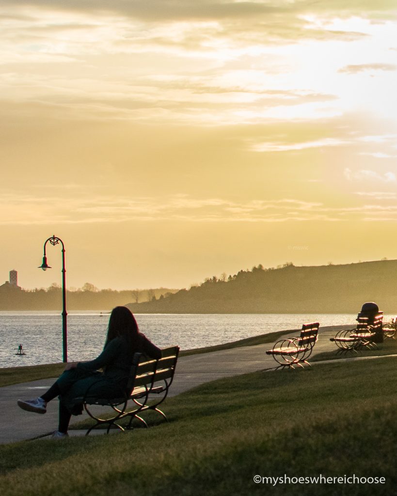 Sunrise at Castle Island and girl on a bench